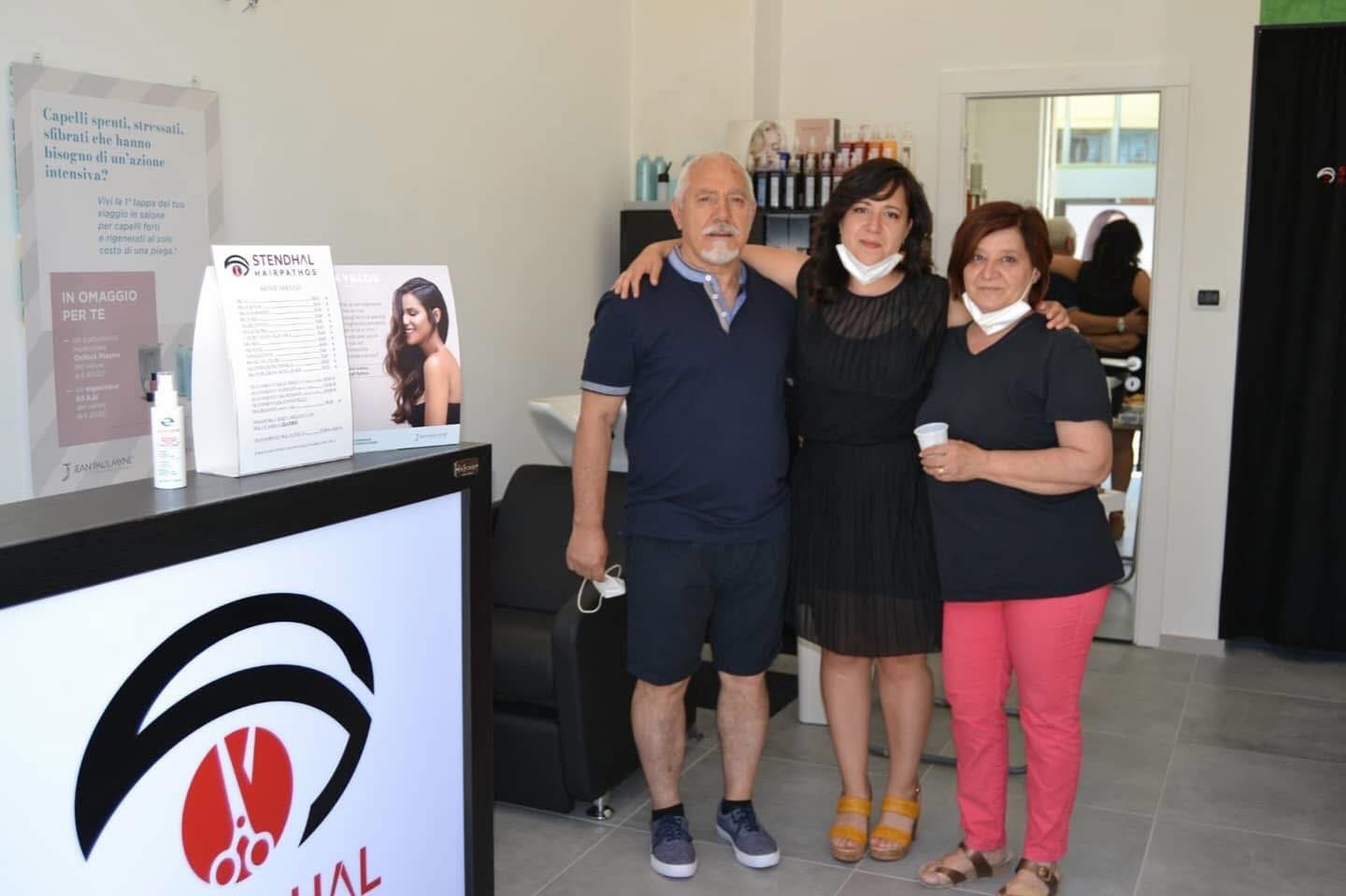 Persone del salone accanto al banco con il logo Stendhal Hairpathos